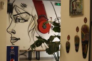 uma parede com uma pintura de uma mulher e um relógio em Nomads Hotel em Amã