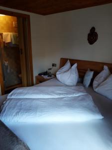 1 dormitorio con 1 cama con sábanas y almohadas blancas en Haus Antonius, en Sankt Lorenzen im Lesachtal