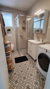 a bathroom with a shower and a washing machine at Salona Garden Apartman in Solin