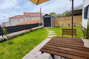 a wooden bench in a yard with a fence at Salona Garden Apartman in Solin