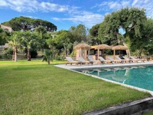 a pool with lounge chairs next to a grass field at Villa CARIOCA St Tropez in Saint-Tropez