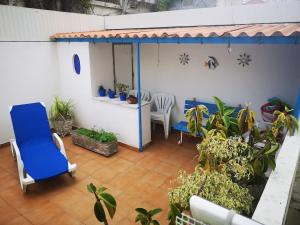 a patio with a blue chair and some plants at Caparica Lounge & Terrace in Costa da Caparica