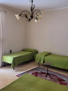 Zimmer mit 2 grünen Betten und einem Kronleuchter in der Unterkunft Casa Murales in Diamante