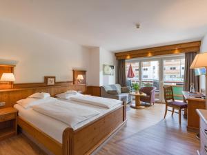 a bedroom with a large bed and a living room at Hotel & Alpin Lodge Der Wastlhof in Niederau