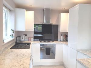 a kitchen with white cabinets and a stove top oven at The Little Red House in Sheffield