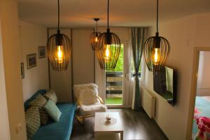 a living room with a blue couch and chandeliers at Emerald Luxury Apartments in Plitvička Jezera