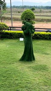 a statue of a woman with a bush on the grass at Hotel Cipron Inn in Udala