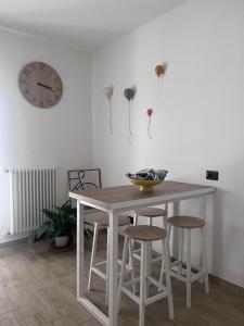 a dining room table and stools with a clock on the wall at B&B Archimede in Scanzano