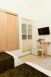 a hotel room with two beds and a desk and a tv at William's Guest House in Jerusalem