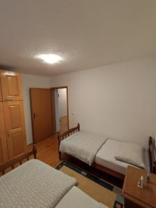 1 dormitorio con 2 camas, mesa y puerta en Barišić, en Livno
