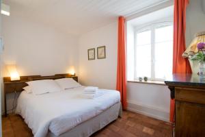 Un dormitorio con una cama blanca con cortinas naranjas y una ventana en Maison de vacances Les Mésanges, à Ménessaire, en Ménessaire