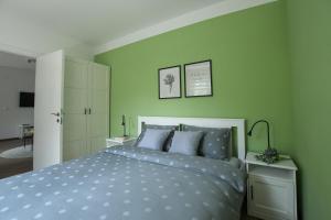 a bedroom with green walls and a bed with blue pillows at Apartman Plaža 2 in Kladovo