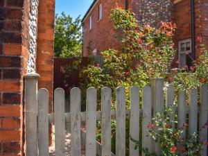 une clôture blanche devant une maison fleurie dans l'établissement Flint House, à Sheringham