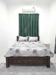 ein Schlafzimmer mit einem Bett mit einem grünen Vorhang in der Unterkunft Homestay Tok Kah in Kuala Terengganu