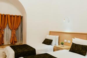 a bedroom with two beds and a window with orange curtains at William's Guest House in Jerusalem