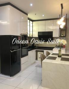 a kitchen with white cabinets and a black refrigerator at Hotspring 2Room Oasis Suit @ Sunway Onsen with Theme Park View(5pax) in Tambun