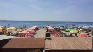 a beach with many umbrellas and chairs and the ocean at La Casa di Pepe in Pietra Ligure