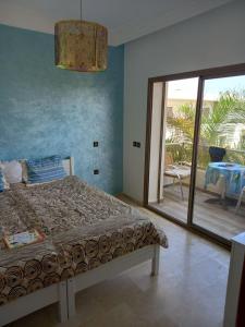 um quarto com uma cama e uma porta de vidro deslizante em Magnifique villa avec piscine privée dans une résidence sécurisée em Sidi Rahal