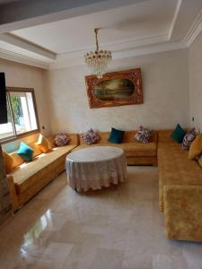 uma sala de estar com sofás e um lustre em Magnifique villa avec piscine privée dans une résidence sécurisée em Sidi Rahal