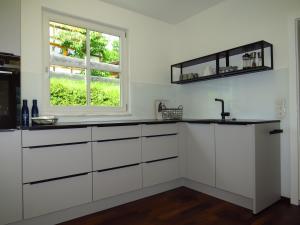 una cocina con armarios blancos y una ventana en Art Appartement, en Niedernsill