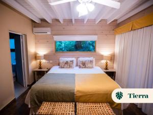 a bedroom with a bed with two tables and a window at La Reserva Virgin Lodge in Puerto Iguazú