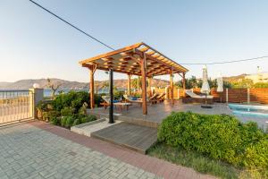 een paviljoen met een tafel en stoelen naast een zwembad bij Niovi Seaside Suites in Kissamos