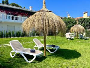two chairs and an umbrella in the grass at Angeles Beach II by ELE Apartments in Vélez-Málaga