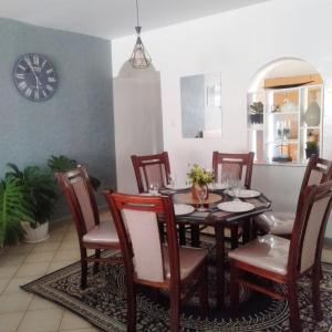 une salle à manger avec une table, des chaises et une horloge dans l'établissement Cosy, serene and affordable 2bdr apartment off Waiyaki way, à Nairobi