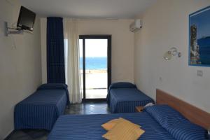 a bedroom with two beds and a view of the ocean at Hotel Jonic in Portopalo