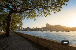 uma árvore ao lado de um corpo de água com montanhas em Apto com VAGA entre Botafogo e Copacabana no Rio de Janeiro