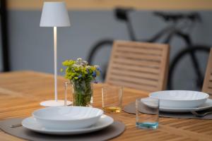 a wooden table with two plates and a vase of flowers at Villetta al lago in Nago-Torbole