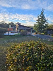 a house in a yard with a bush in front of it at Complejo Sol in Villa Carlos Paz