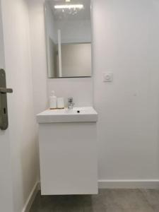 a white bathroom with a sink and a mirror at Le Cottage in Pamiers