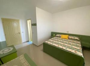 a bedroom with a green bed with a yellow pillow at Qerana's rooms: Corner of nature in Golem