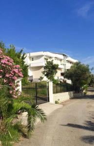 a white apartment building with a fence and pink flowers at Qerana's rooms: Corner of nature in Golem