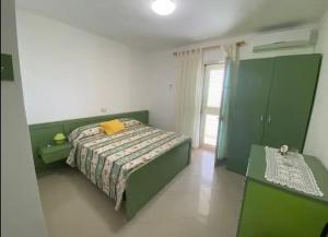 a bedroom with a green bed and a window at Qerana's rooms: Corner of nature in Golem