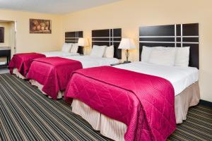 2 łóżka w pokoju hotelowym z różowymi kocami w obiekcie Soudersburg Inn & Suites Lancaster w mieście Ronks