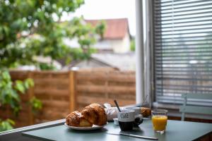 una mesa con un plato de pan y un vaso de zumo de naranja en Le coquet chez Maguy Maison de ville avec jardin en Besanzón