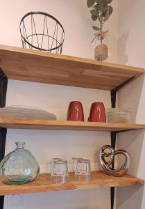 a shelf with bowls and dishes on it at Studio Calme Hyper Centre Brive in Brive-la-Gaillarde