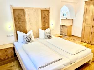 ein Schlafzimmer mit einem großen Bett mit weißer Bettwäsche in der Unterkunft Chalet Bernardi Apartments in St. Ulrich in Gröden