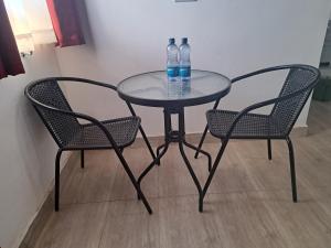 two water bottles sitting on a glass table with two chairs at Jazby Guest House, Naivasha in Naivasha