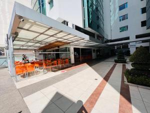 a building with orange tables and chairs in a courtyard at Departamento lujo 2 habitaciones, sobre la República de El Salvador y Portugal, Plaza Kendo. in Quito