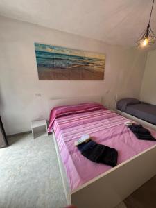 Un dormitorio con una cama rosa con una pintura en la pared en Totò’s house, en Zaccanopoli