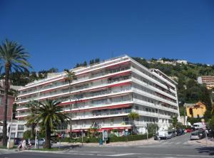 a large white building with palm trees in front of it at Studette 1 pièce in Menton