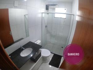uma casa de banho com um chuveiro, um lavatório e um WC. em TH Flats GV em Governador Valadares