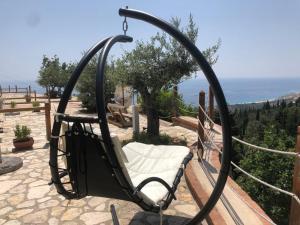 a swinging chair on a patio with a view of the ocean at Rahoni Park & Suites in Dhërmi