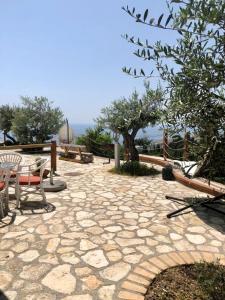 a stone patio with chairs and tables and a tree at Rahoni Park & Suites in Dhërmi