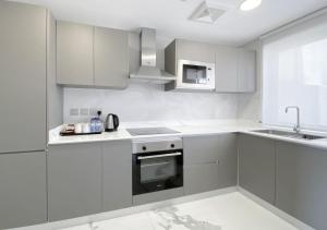 a white kitchen with white cabinets and a sink at The Sea Loft Boutique Chalets in Manama