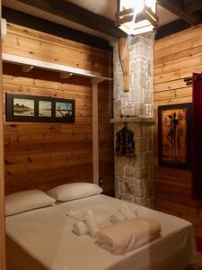 a bed in a wooden room with towels on it at Rahoni Park & Suites in Dhërmi