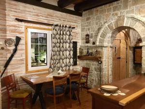 a dining room with a table and a stone wall at Rahoni Park & Suites in Dhërmi